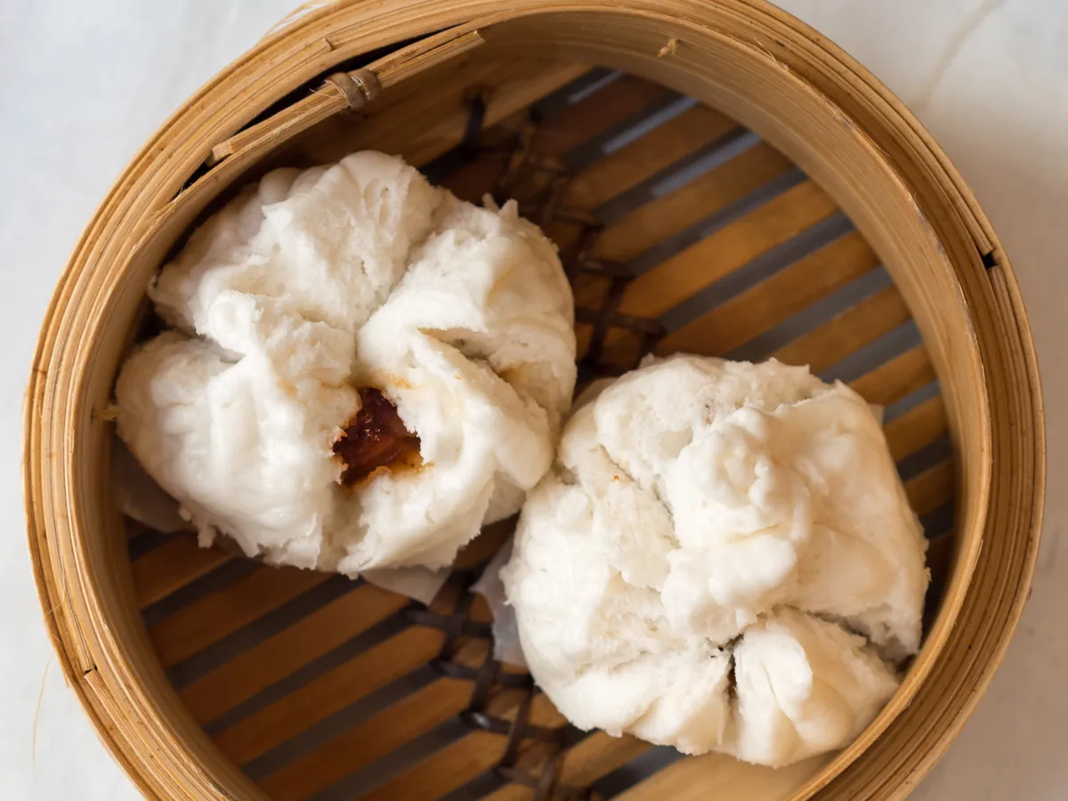 Steamed char siu bao opened to show the barbecue pork filling